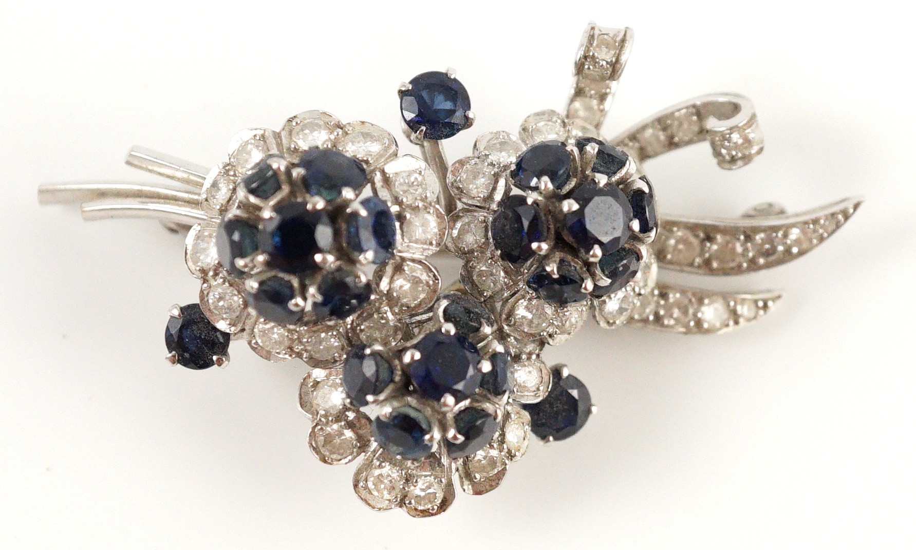 A white gold, sapphire and diamond cluster set floral spray brooch